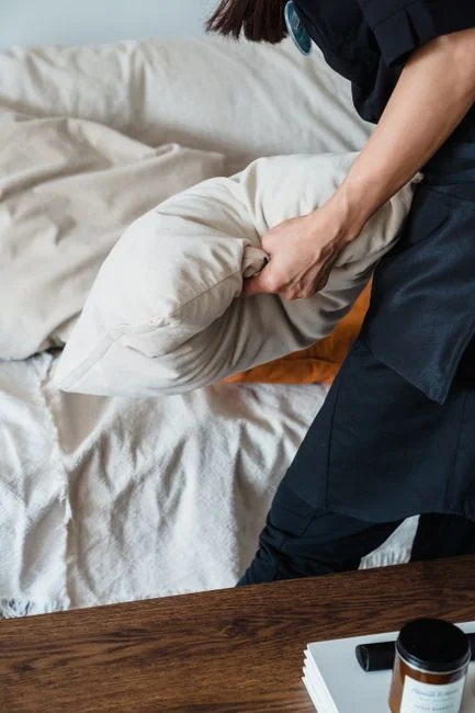 Housekeeper organizing towels in a hotel room, showcasing the art of cleanliness and service.